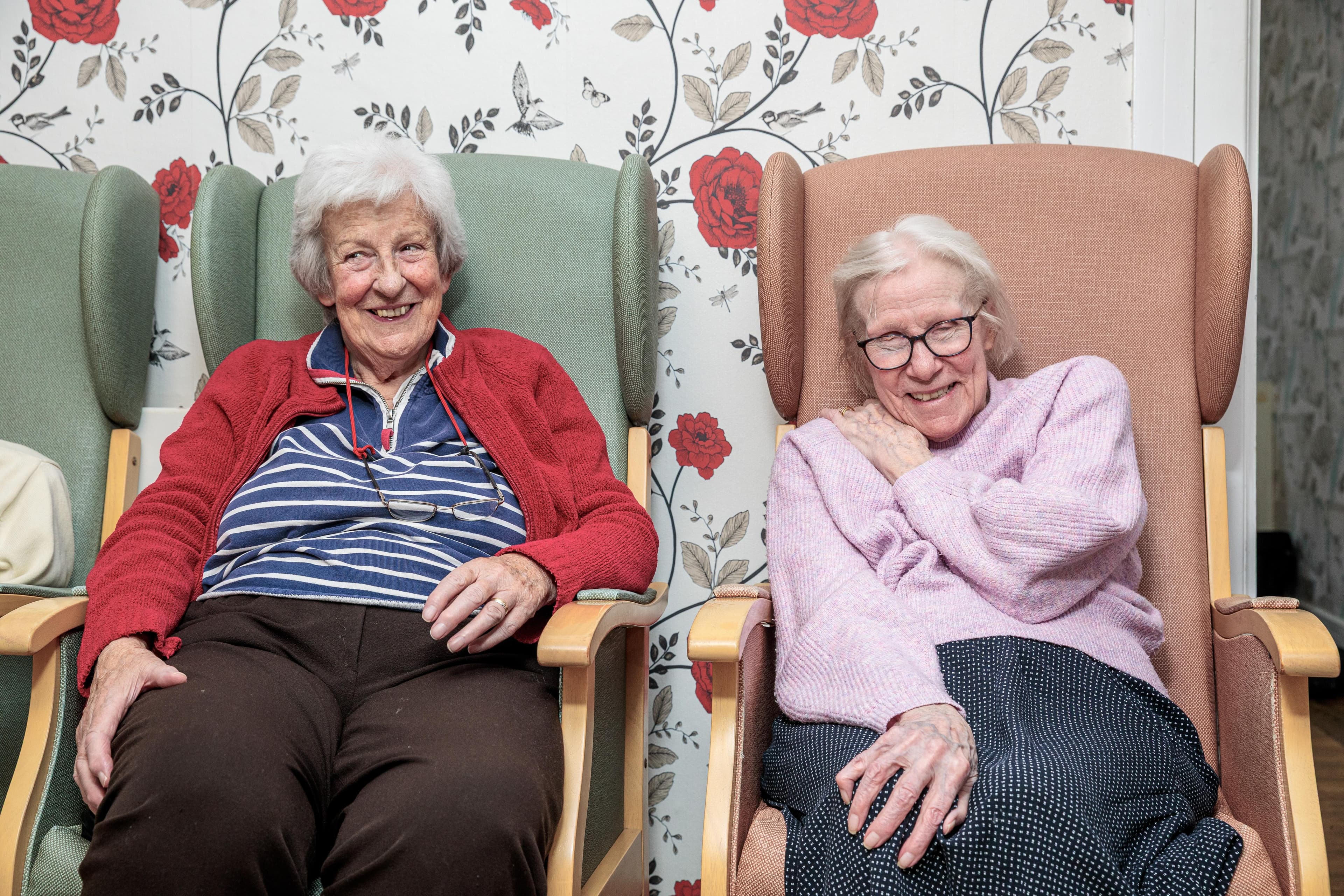 Two smiling residents relaxing in armchairs